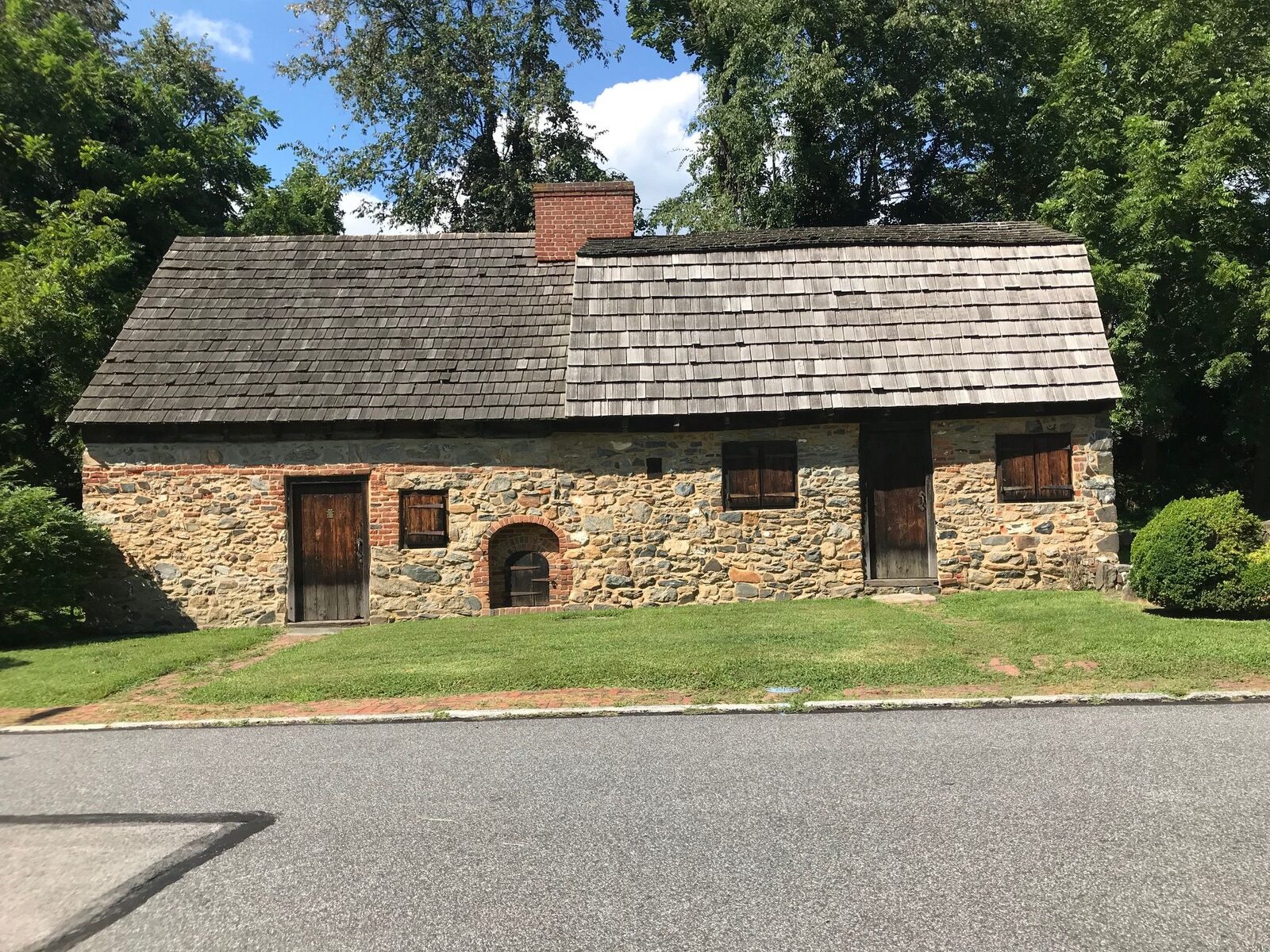 Front elevation of a small seventeenth-century stone and stucco colonial house with a steep shingled roof